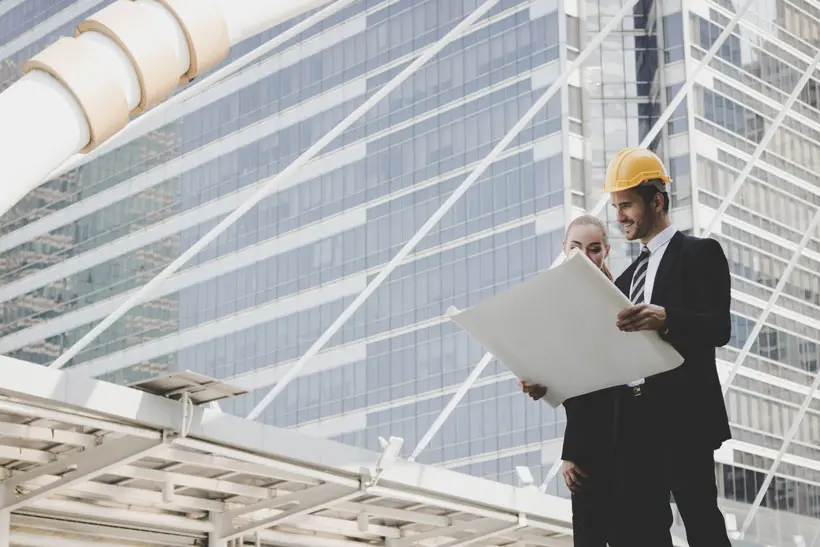 Equipo empresarial analizando plano estrategico frente a edificio corporativo como representacion visual de desarrollo de SEO profesional en Queretaro