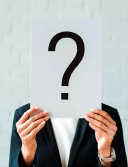 Persona con traje sosteniendo signo de interrogacion frente a camara como representacion de empresas sin identidad digital definida que necesitan desarrollo de sitio web en Queretaro