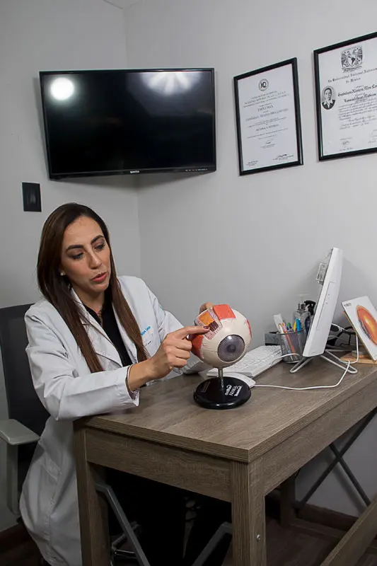 Dra Ximena Mira explicando modelo anatomico de ojo en su consultorio en Queretaro