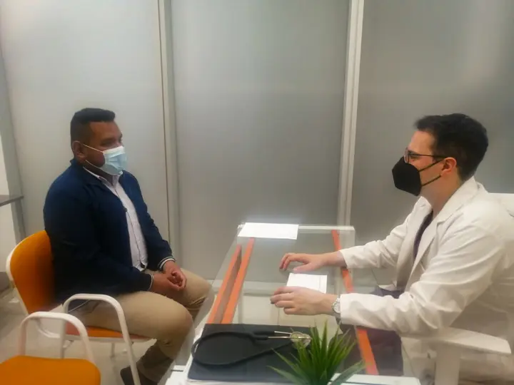 Oncólogo con bata blanca y cubrebocas atendiendo a un paciente durante una consulta en consultorio privado, ejemplo de publicidad para médicos especialistas enfocada en cáncer de pulmón.